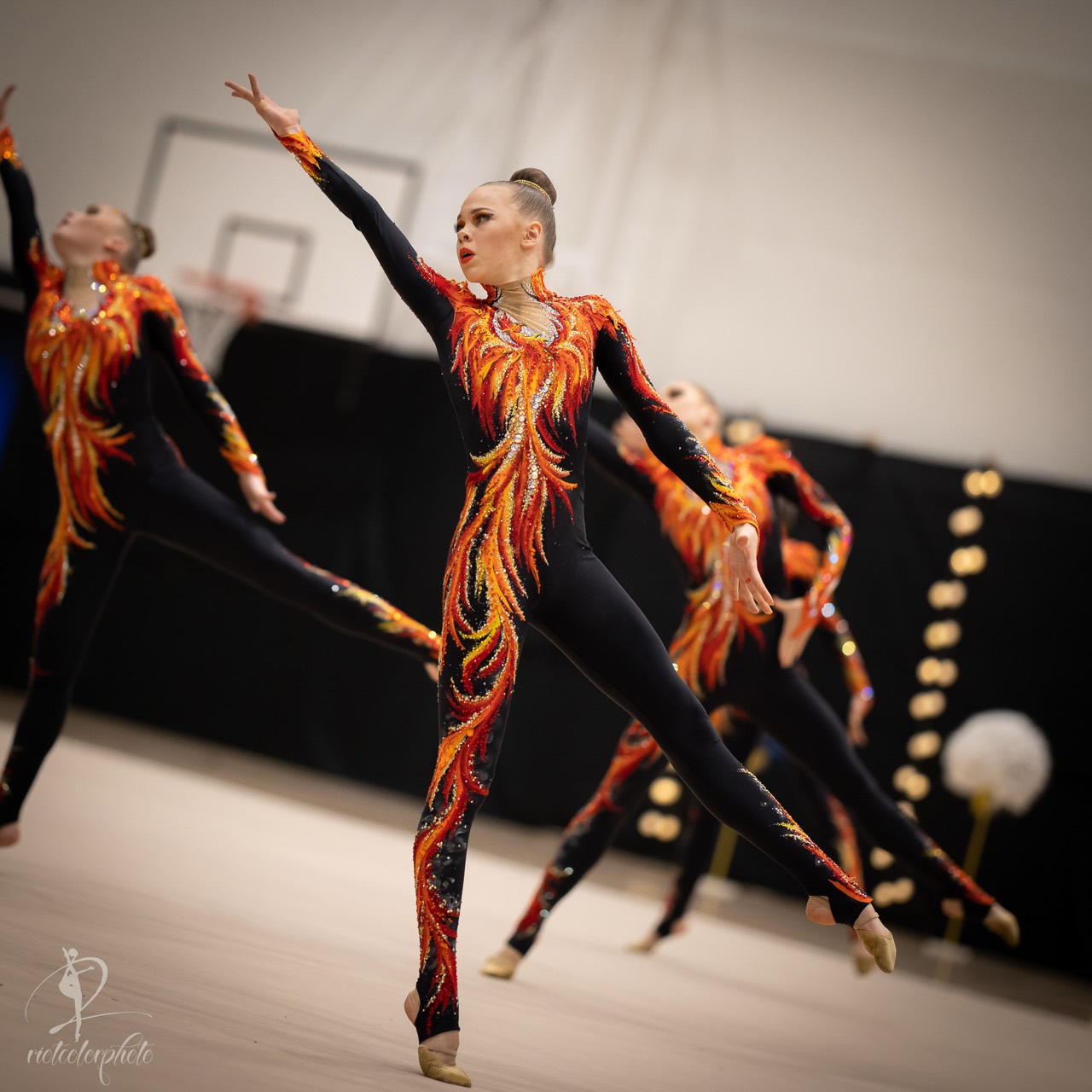 Gymnast performing in a black and orange unitard